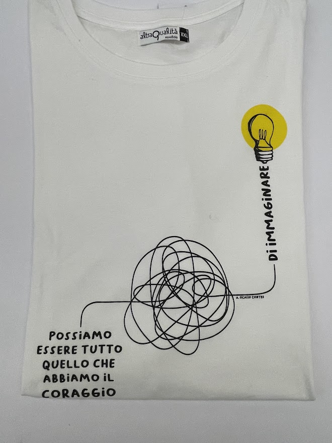 Maglietta bianca a manica corta con il disegno di un circuito elettrico e la frase "Possiamo essere tutto quello che abbiamo il coraggio di immaginare"